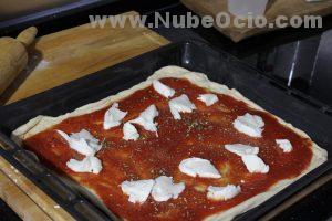 Echando mozzarella a la pizza