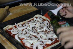 Añadiendo aceite de oliva a la pizza con un pincel